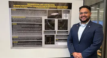 Sergio Perez stands next to a display board full with text from his summer research