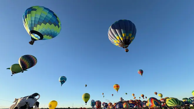 Several colorful hot air balloons lift off at the Albuquerque Balloon Fiesta