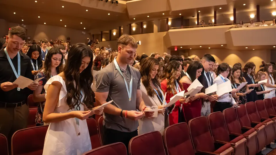 A crowd of students reads the Nightingale Pledge from a pamphlet