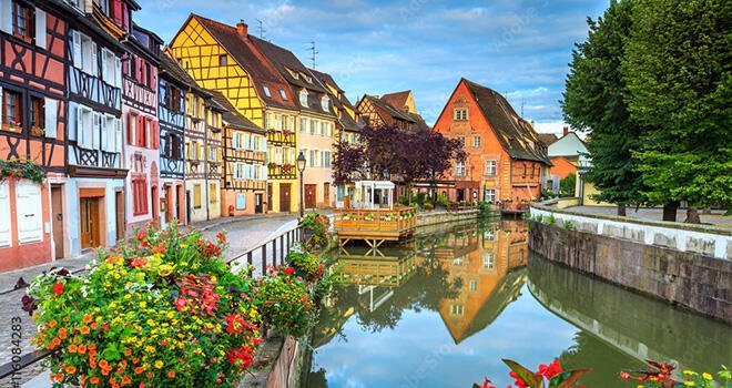 Colorful medieval half-timbered facades reflecting on water in Colmar, France